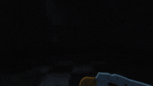 a yellow glowing object in a dark room with a checkered wall