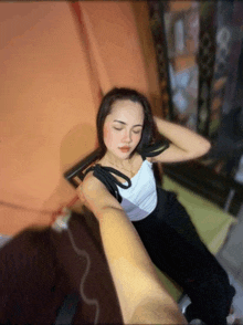 a woman in a white top and black pants is laying on a bed