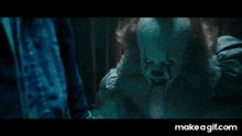pennywise the clown is standing in front of a person in a dark room .
