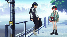a girl sitting on a railing next to a girl with a red hat