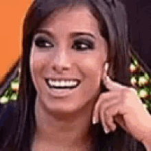 a close up of a woman 's face smiling and touching her face .