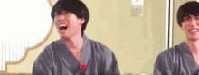 two men in kimonos are laughing and sitting next to each other .