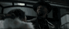 a man wearing a top hat is standing in a dark room .