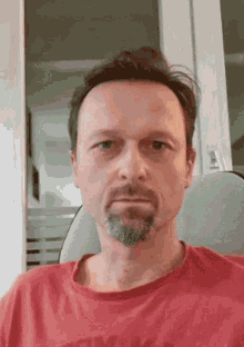 a man with a beard wearing a red shirt that says tommy hilfiger