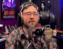 a man wearing headphones and glasses stands in front of a microphone
