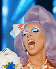 a close up of a drag queen with purple hair and makeup