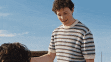 a man wearing a striped shirt is standing next to another man