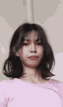 a woman wearing a pink shirt is looking at the camera