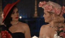 a woman in a red hat and a woman in a pink hat look at each other