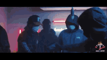 a group of people wearing face masks and hoodies are standing in a room