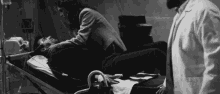 a black and white photo of a man laying in a hospital bed while a doctor looks on