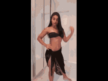 a woman in a black bikini is dancing in front of a mirror with kwai in the corner