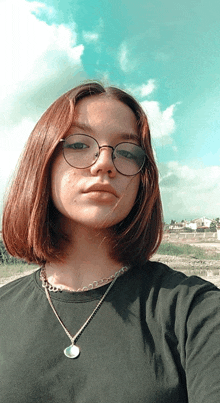 a young girl wearing glasses and a necklace takes a selfie