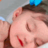 a baby girl with a blue bow on her head is sleeping