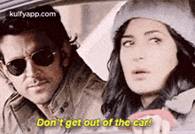 a man and a woman are sitting in a car and the woman is driving .