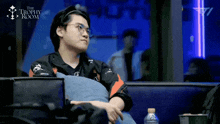 a man sits in the trophy room with a bottle of water next to him