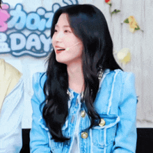 a woman wearing a blue jacket is sitting in front of a sign that says ' dont day '