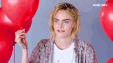 a woman in a plaid shirt is holding a red balloon with marie claire written on the bottom of the image