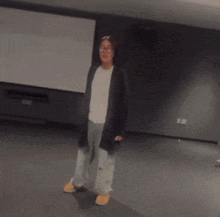 a woman wearing glasses and a black cardigan stands in a room