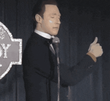 a man in a tuxedo and bow tie is giving a thumbs up