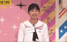 a young girl in a sailor suit is standing in front of a colorful wall .