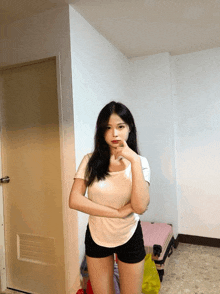 a woman standing in a room with her arms crossed and a pink suitcase behind her