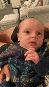 a baby is being held by a person wearing a blue pajama that says roar on it