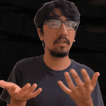 a man wearing glasses and a black shirt has his hands outstretched