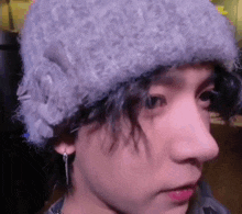 a close up of a person wearing a knitted hat and earrings .