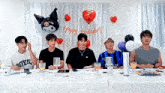a group of young men are sitting at a table with balloons and a balloon that says happy birthday on it .