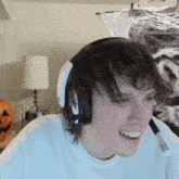 a man wearing headphones is smiling in front of a pumpkin .