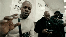a group of men are standing in a laundromat looking at their phones