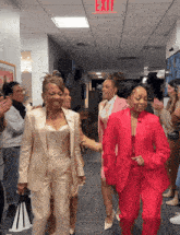 a red exit sign is above a group of women in suits