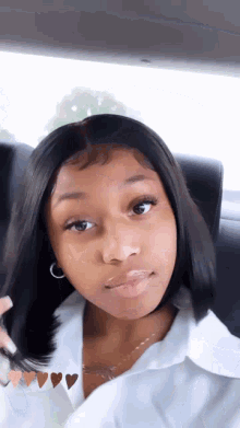a young girl is sitting in the back seat of a car with her hair in her hand .