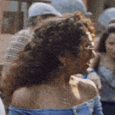 a woman wearing glasses and a blue off the shoulder top is standing in a crowd .