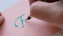 a person is writing the letter f on a piece of paper .