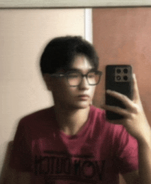 a young man taking a picture of himself in a mirror while wearing glasses