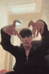 a man in a black jacket making a heart shape with his hands