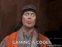 a man in an orange vest is making a funny face and says `` gaming is cool '' .