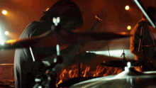 a man playing drums in front of a crowd with a microphone in the background