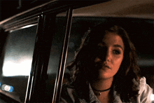 a woman is sitting in the back seat of a car looking out the window .