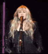 a woman singing into a microphone while holding a guitar