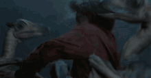 a man in a red shirt is laying on the ground with a snake coming out of his chest .