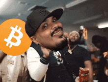 a man wearing a ny hat is holding a coin with a b on it