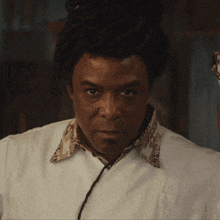 a man with dreadlocks is wearing a white shirt with a floral collar