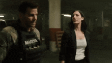 a man and a woman are standing next to each other in a dark room looking at each other .