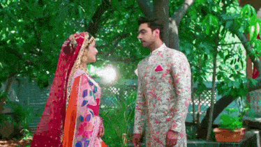 a bride and groom are standing next to each other in front of trees .