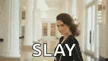 a woman in a black dress is standing in a hallway with the word slay on the bottom