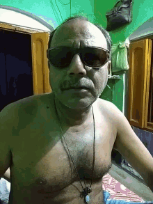 a shirtless man wearing sunglasses and a necklace with a button on it