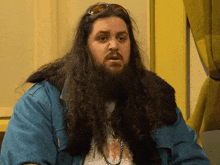a man with a long beard wearing sunglasses and a blue jacket
